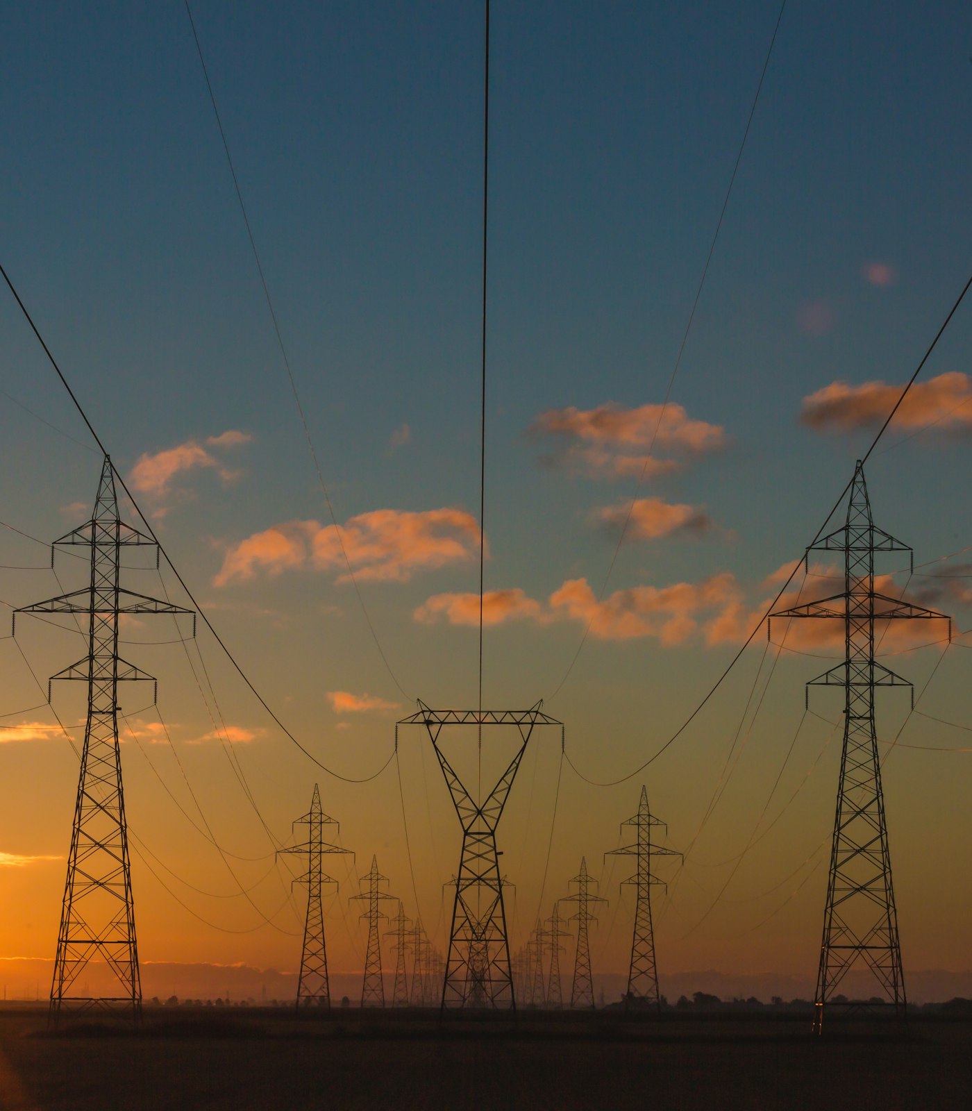 High-voltage transmission towers against a sunset sky